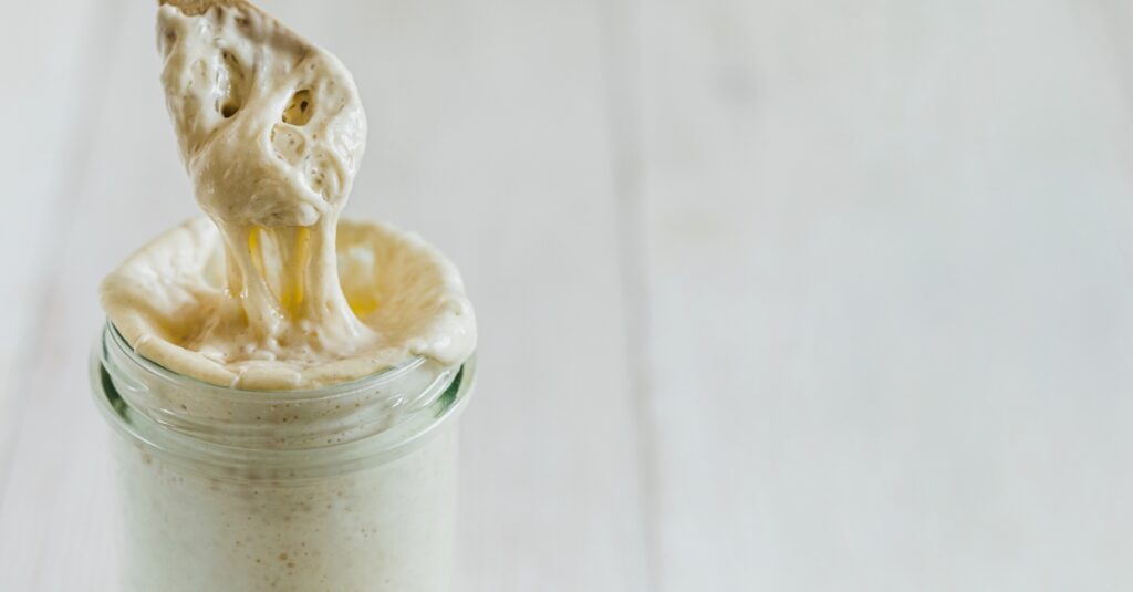 Active sourdough starter rising in a glass jar.